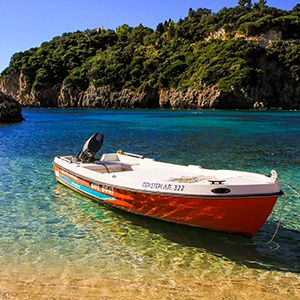 barca sulla riva nel mare cristallino a corfù