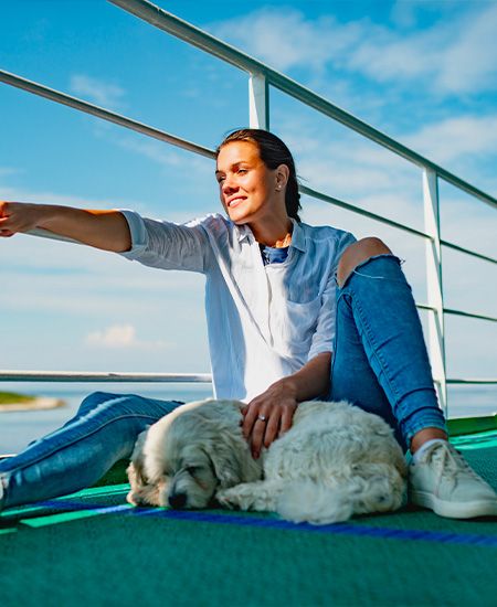 Ragazza sorridente sul ponte di una nave che accarezza un cane bianco